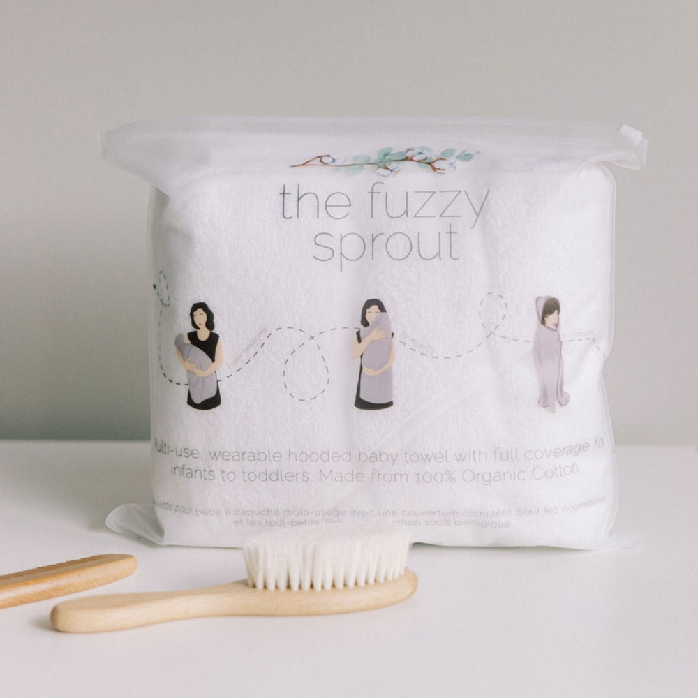 picture of handsfree wearable baby towel in the EVA packaging with a diagram and a baby comb infront.